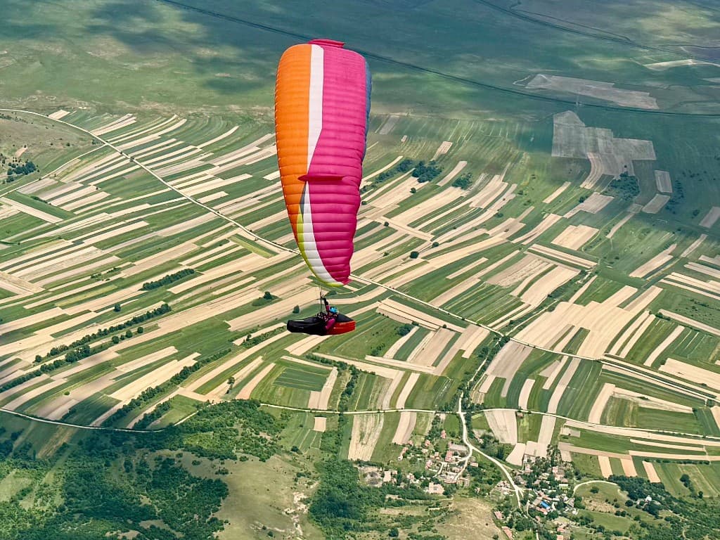 Wing gliding over fields and farmland far below