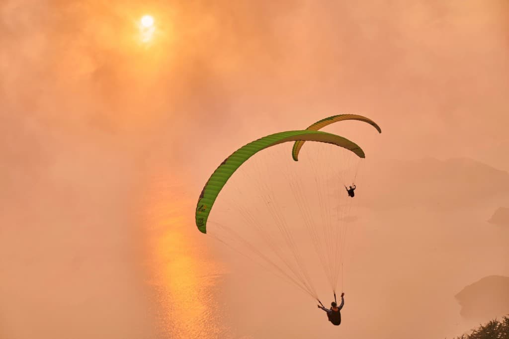 Two paragliders soaring in a glowing sunset sky