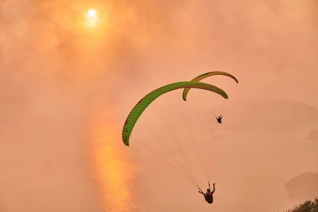 Two paragliders in a glowing sky