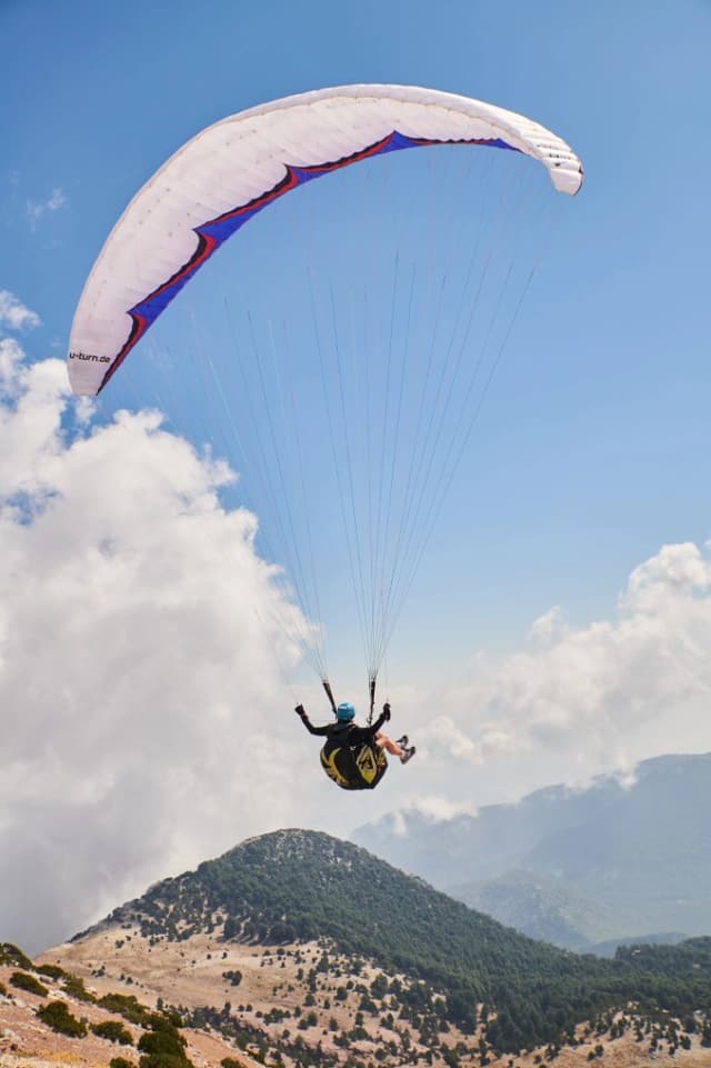 Pilot under a white wing over mountains