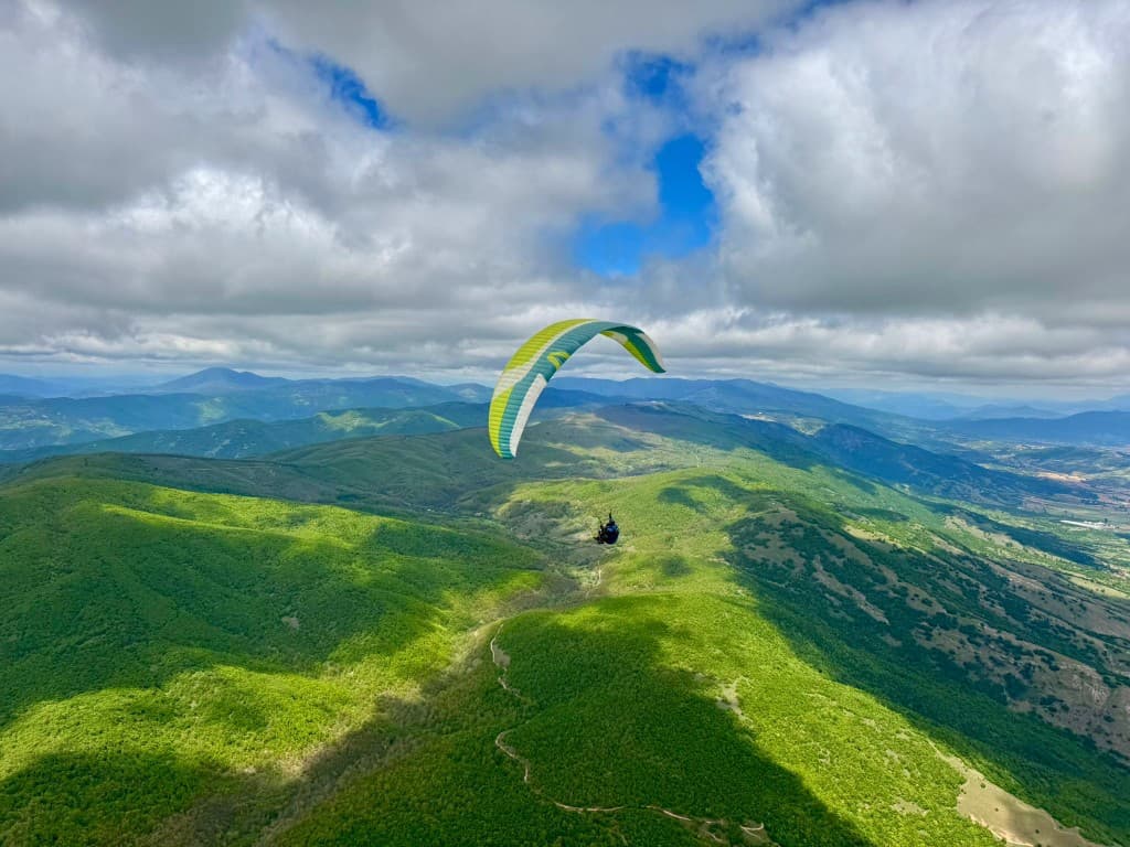 Paraglider over green mountain ridges — Macedonia